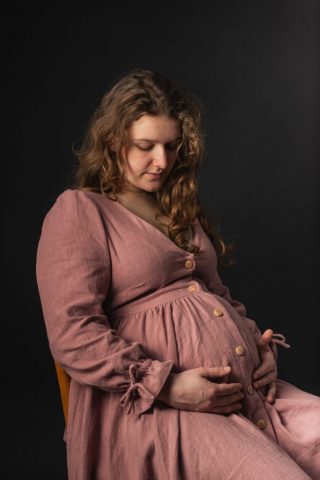 Künstlerisches Schwangerschaftsbild im Studio – werdende Mutter im Seitenlicht vor dunklem Hintergrund