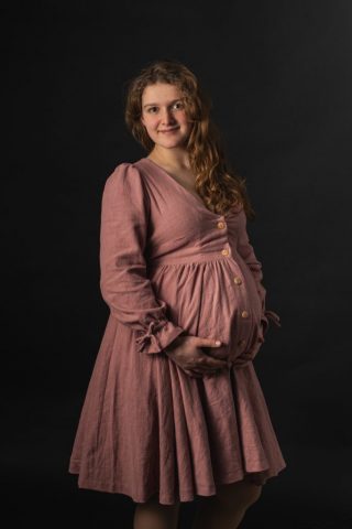 Portrait einer werdenden Mutter im Studio in Kiel, eingefangen im weichen Licht vor dunkler Kulisse