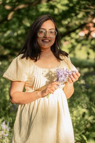 Junge Frau in sommerlicher Naturkulisse mit violetten Blumen und warmem Licht – Outdoor-Portraitfotos in Kiel