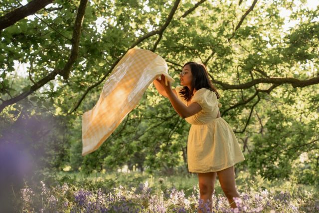 Stimmungsvolle Aufnahme einer jungen Frau zwischen violetten Blumen unter Bäumen im weichen Licht des Abends in Kiel