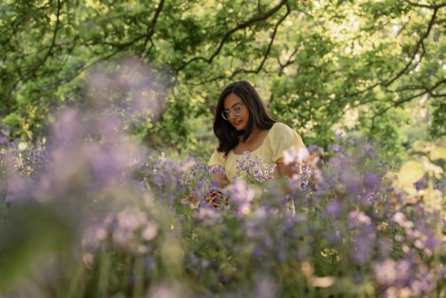 Lesende junge Frau in lila Blumenwiese bei goldenem Licht, umgeben von Natur – Outdoor-Portrait in Kiel