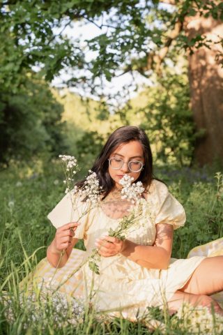 Natürliche Portraitaufnahme einer jungen Frau mit Blumen in der Hand auf einer blühenden Wiese in Kiel