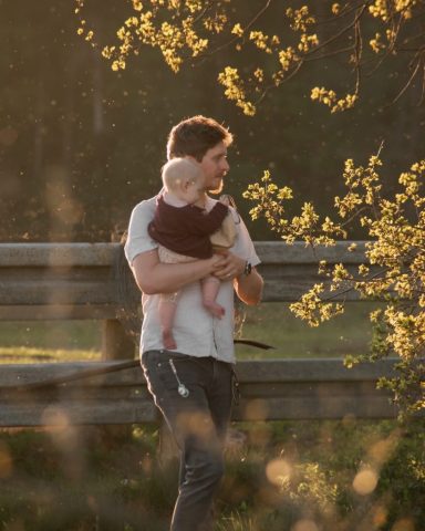Natürliches Porträt eines Vaters mit Baby beim Spaziergang am Strand – goldenes Licht und sanfte Stimmung in Kiel