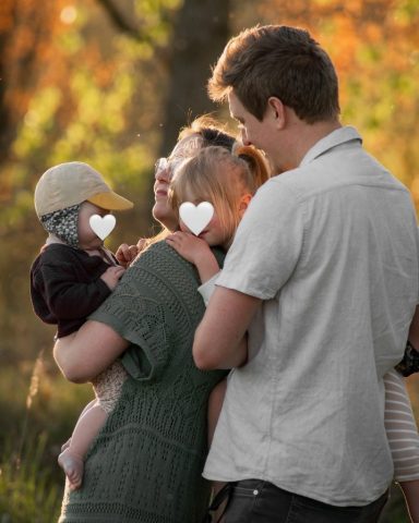 Authentisches Familienfoto in einem Park in Kiel – Baby auf dem Arm, Sonnenuntergang durch die Bäume