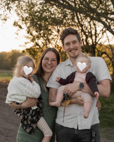 Familienfotoshooting in Kiel: Eltern halten ihre Kinder liebevoll im Arm, warmes Licht im Hintergrund