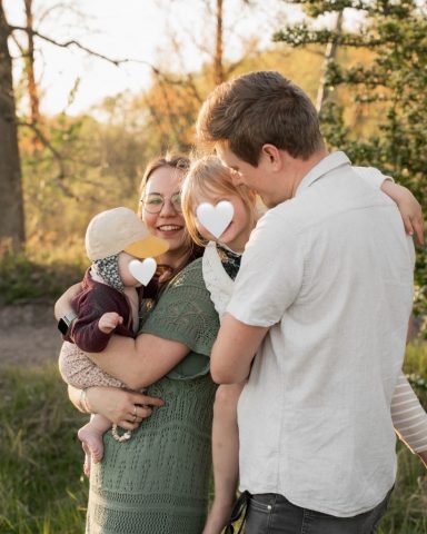 Familienfotoshooting in Kiel: Eltern halten ihre Kinder im Arm, kleine Tochter lächelt direkt in die Kamera