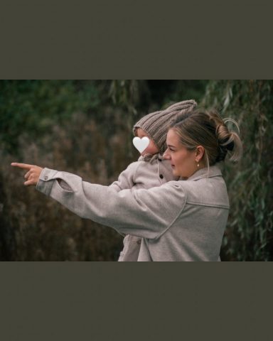 Natürliche Familienaufnahme in Kiel: Mutter hält ihre kleine Tochter an der Hand beim Spaziergang am See im Park