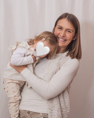 Natürliches Familienporträt im Kieler Studio: Kleine Tochter kuschelt sich liebevoll an ihre Mutter