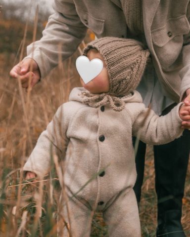 Porträt eines kleinen Mädchens im hohen Gras im Park in Kiel, mit der Mutter unscharf im Hintergrund