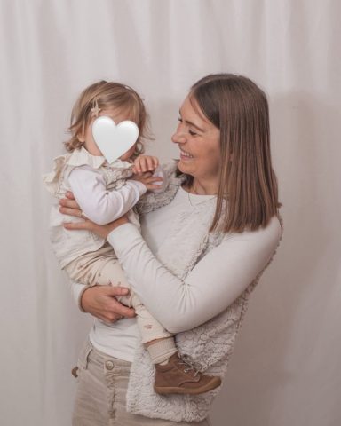 Natürliches Familienporträt im Kiel: Kleine Tochter kuschelt sich liebevoll an ihre Mutter