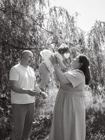 utter und Vater genießen einen fröhlichen Moment mit ihrer Tochter, die in die Luft gehoben wird – Familienfoto in Kiel