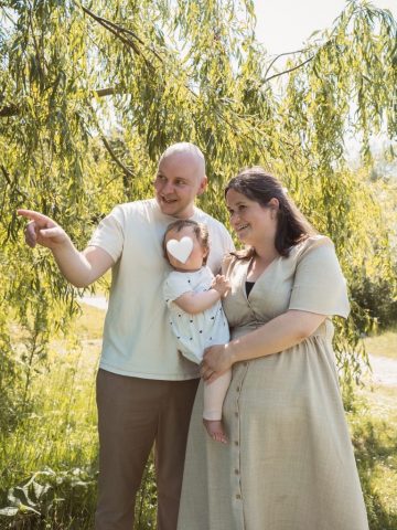 Familienportrait mit einer Weide im Hintergrund, aufgenommen im hellen Tageslicht – Fotoshooting zum 1. Geburtstag in Kiel