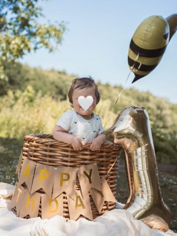 Kleines Mädchen feiert ihren ersten Geburtstag, sitzt im Korb mit 1er-Ballon und Dekoration – Familienfotoshooting in Kiel