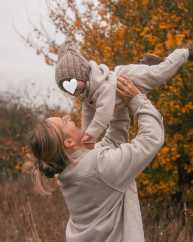 Fröhlicher Familienmoment in Kiel: Mutter hält lachend ihre kleine Tochter hoch in die Luft, beide voller Freude