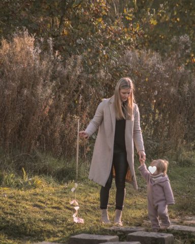 Mutter spaziert im Park in Kiel mit ihrer kleinen Tochter und hält sie liebevoll an der Hand