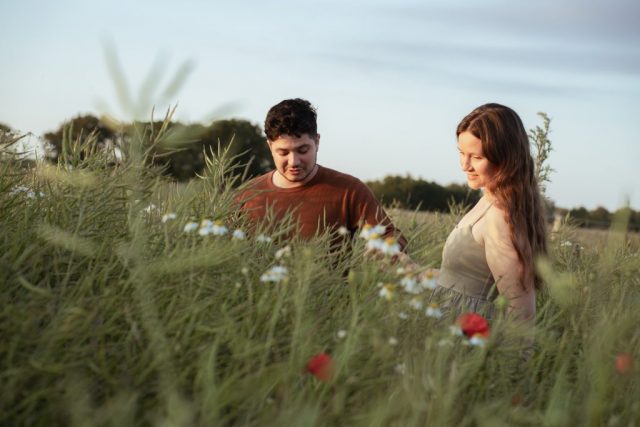 Romantisches Paar im Sonnenuntergang, umgeben von wildem Blumenfeld. Outdoorfotoshooting im Sommer