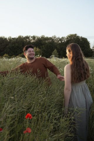 Fröhlicher Moment zwischen zwei Menschen im offenen Feld mit blühenden Blumen im Abendlicht