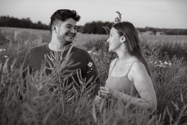 Romantisches Paar im Abendlicht, umgeben von bunten Wildblumen auf einer grünen Wiese. Schwarz-Weiß