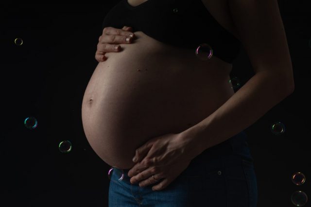 Detailbild vom schwangeren Bauch im Studio, im sanften Licht fotografiert